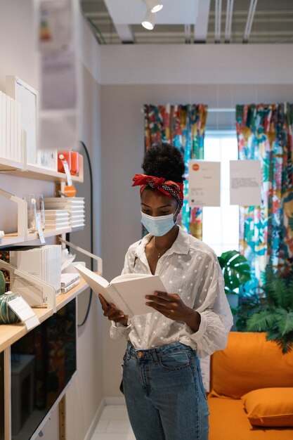 Black woman reading book in book store during quarantine period