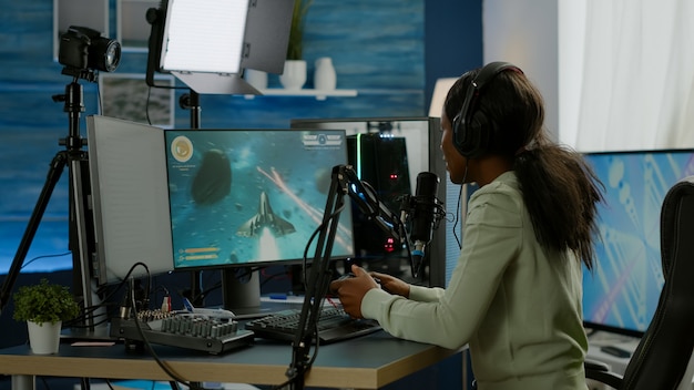 Free photo black woman streamer playing space shooter videogames with joystick talking with teammates on streaming open chat. cyber performing on rgb powerful computer in gaming room using professional equipment