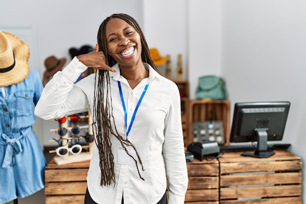 Free Photo black woman with braids working as manager at retail boutique smiling doing phone gesture with hand and fingers like talking on the telephone. communicating concepts.