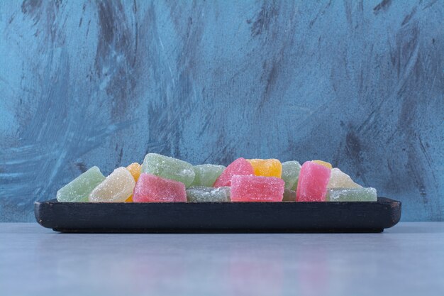 A black wooden board full of colorful fruit sugary marmalades 