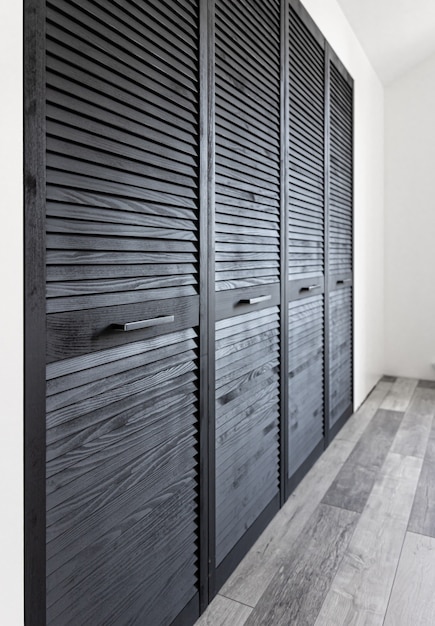 Black wooden wardrobe decorated with blinds, wardrobe with blinds decoration.