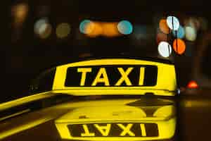 Free photo black and yellow sign of taxi at night placed on top of a car