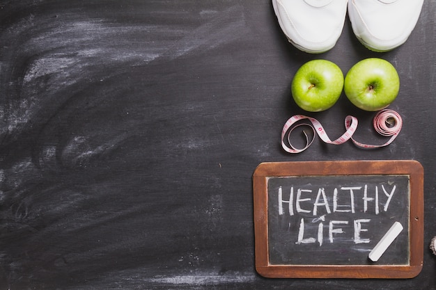 Blackboard background with sneakers, apples and tape measure