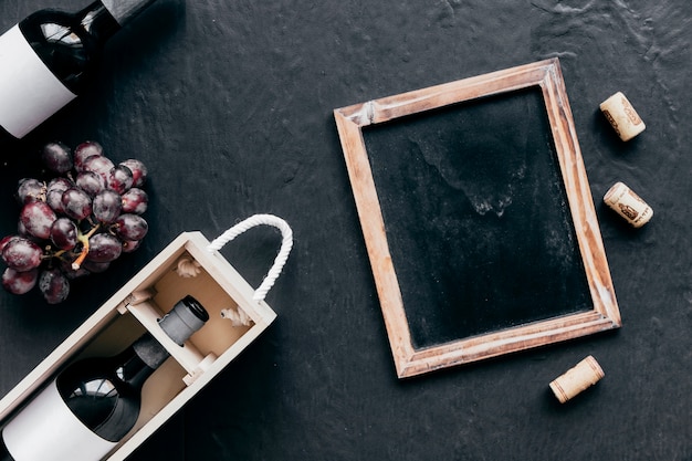 Free photo blackboard and corks near bottles and grape