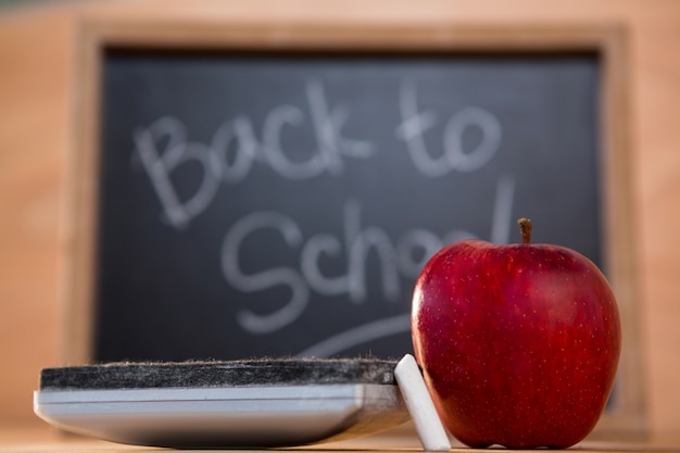 Free photo blackboard duster with red apple and chalk