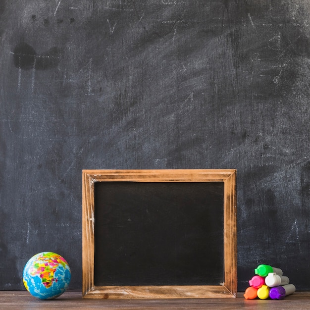 Free photo blackboard frame with glove and markers