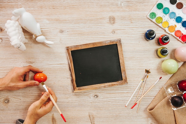 Free photo blackboard and person painting egg