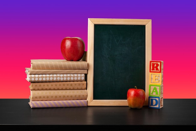 Free Photo blackboard and stacked books against colored background