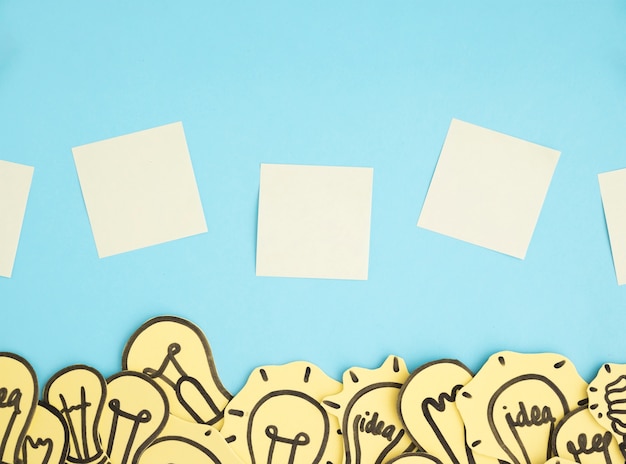 Free photo blank adhesive notes over the border of many light bulbs against blue background