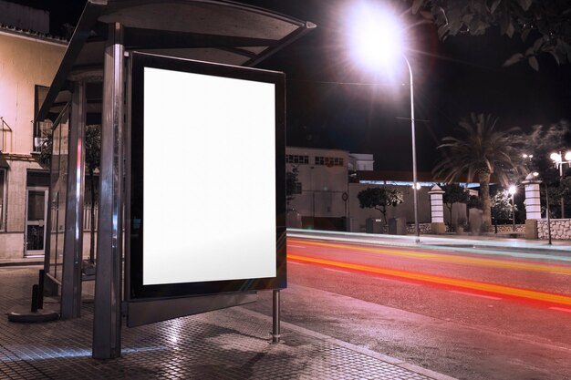 Blank advertisement at bus shelter with blurred traffic lights at night