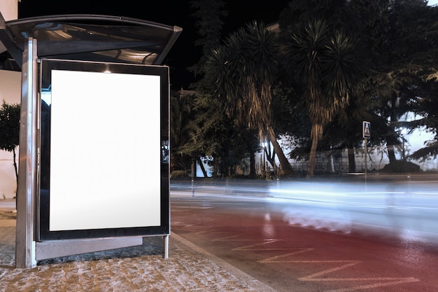 Blank billboard on bus stop shelter at night