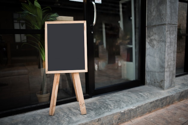 Free photo blank black chalk board in front of the cafe