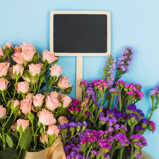 Free photo blank blackboard label inside the flower bouquet against blue background