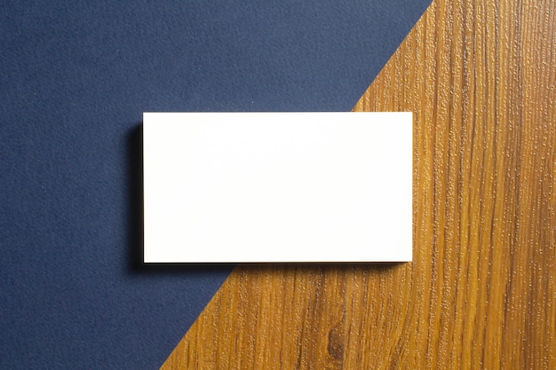 Free photo blank business cards half of each lie down on blue textured  paper and wooden desk