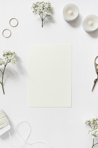 Free photo blank card surrounded with gypsophila; wedding rings; string and scissor on white background