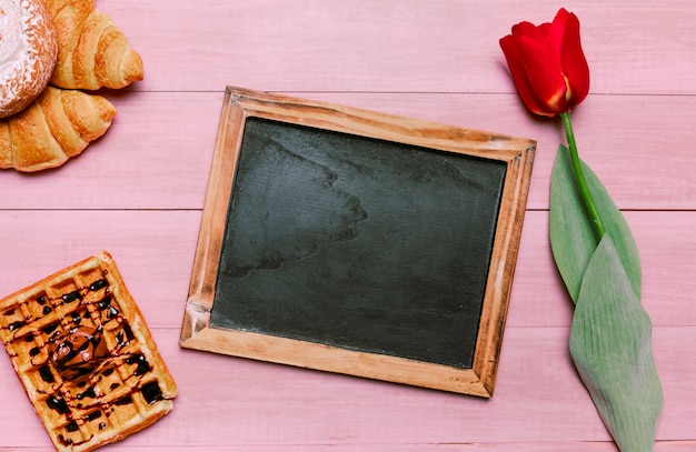 Free photo blank chalkboard with belgian waffle and tulip