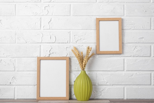 Free photo blank frame collection on wall and next to vase