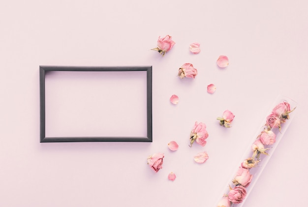 Free Photo blank frame with rose petals on table