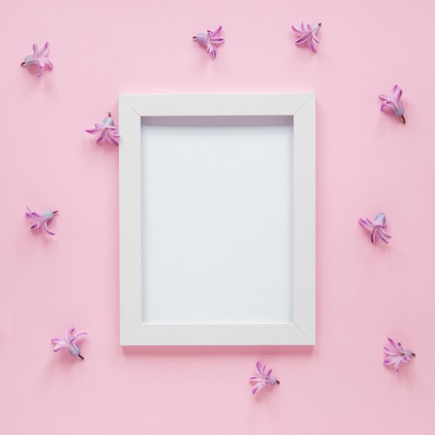 Blank frame with small purple flowers on table 