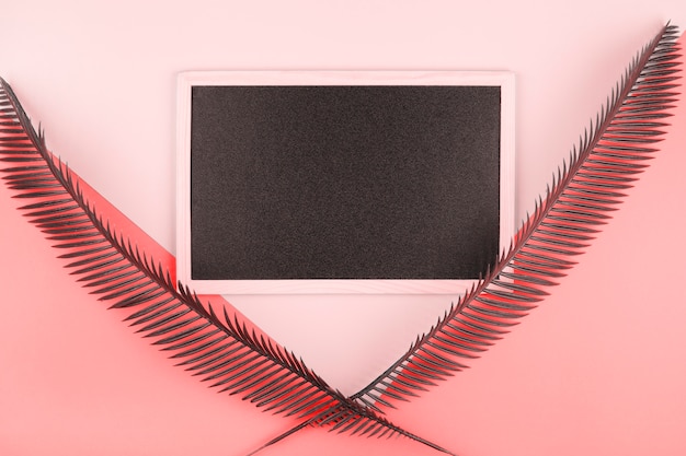 Free Photo blank miniature blackboard decorated with palm leaves over the pink and coral backdrop