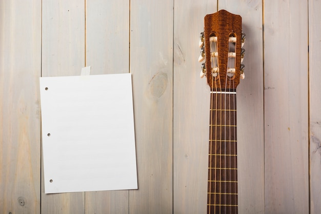 Free photo blank musical page stuck on wooden wall with guitar's head