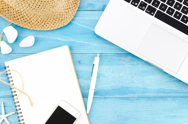 Blank notebook with straw hat and laptop