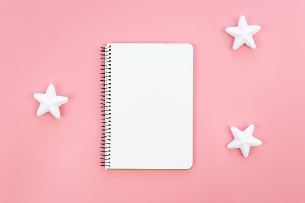 Free photo blank notepad on pink background and decorative stars flat lay