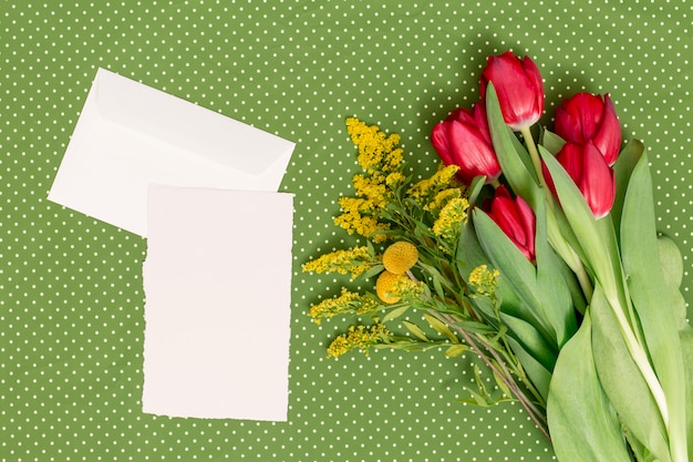 Free photo blank paper; envelope with flowers over green background on mother's day