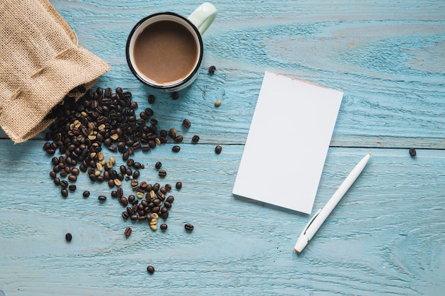 Free Photo blank paper; pen with cup of a coffee and coffee beans on blue textured table