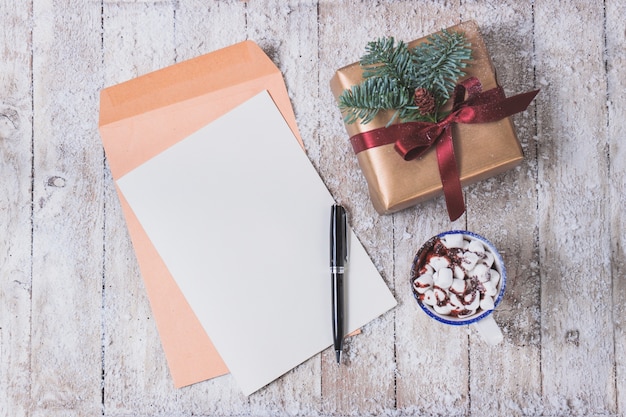 Free photo blank paper with a ballpoint pen and cup with marshmallows and a gift