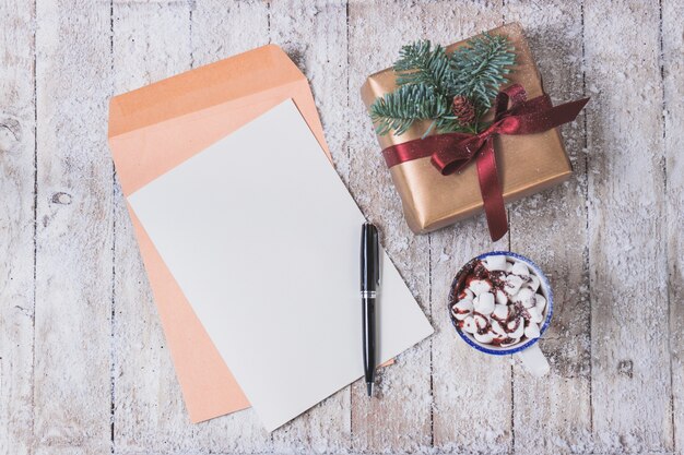 Blank paper with a ballpoint pen and cup with marshmallows and a gift