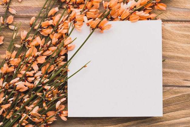 Free Photo blank paper with flowers on wooden surface