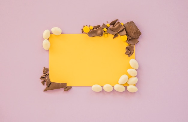 Free photo blank paper with small candies and cracked chocolate