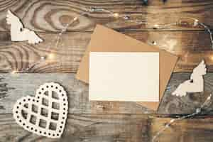 Free photo blank paper and wooden heart on wooden background flat lay