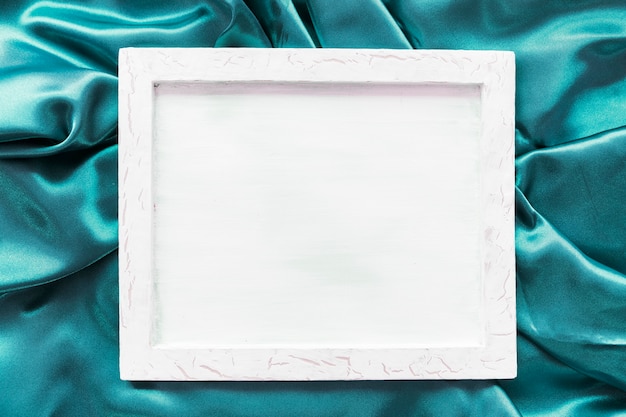 Free Photo blank picture frame on turquoise satin fabric