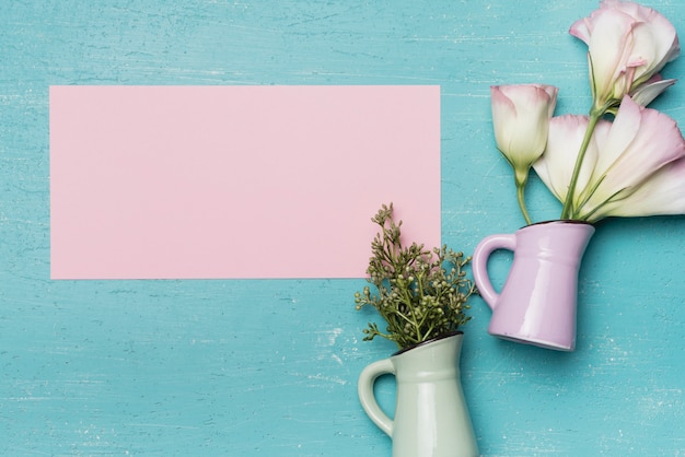 Blank pink paper with two ceramic vase on blue background