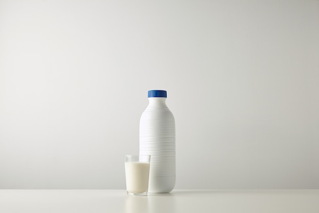 Free photo blank plastic white bottle with blue cap near glass with milk isolated on white table center, rich texture