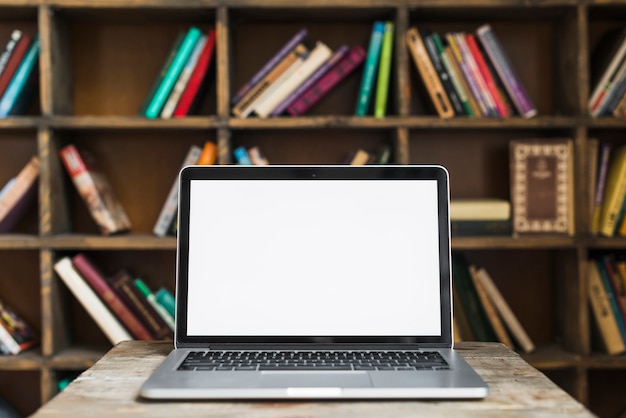 Blank screen open laptop on wooden desk in library