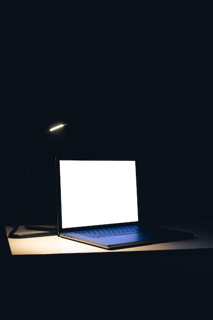 Free photo blank screen workspace with computer laptop on table at night copy space