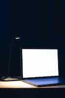 Free photo blank screen workspace with computer laptop on table at night copy space