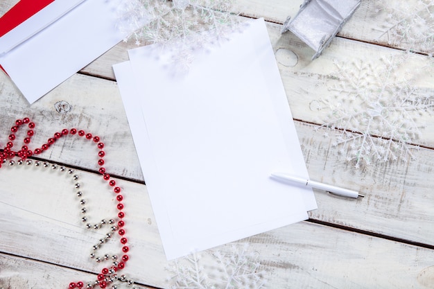 Free photo the blank sheet of paper on the wooden table with a pen and christmas decorations.