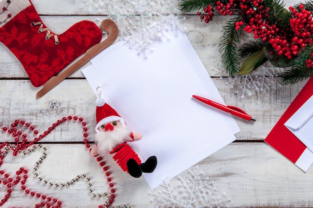 The blank sheet of paper on the wooden table with a pen and Christmas decorations.