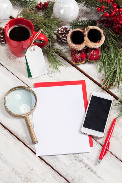 blank sheet of paper on the wooden table with a pen,  phone and Christmas decorations.