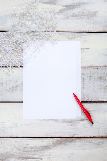 The blank sheet of paper on the wooden table with a pen.