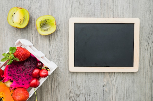 Free photo blank slate and tasty fruits on wooden surface