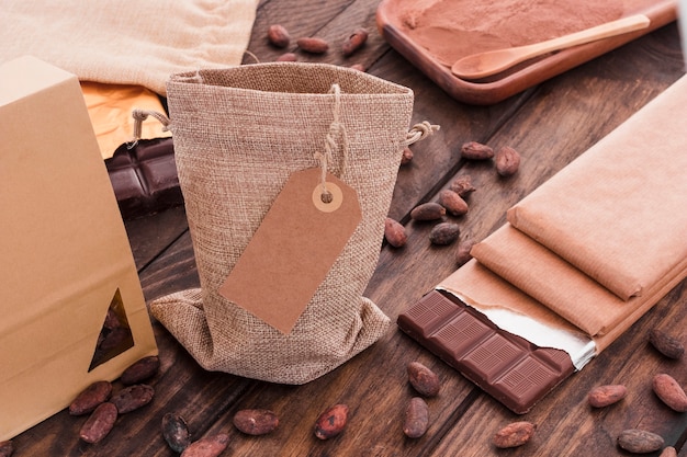 Blank tag on sack with scattered cocoa beans and chocolate bar on table