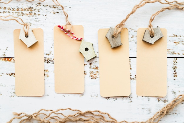 Free Photo blank tags tied with miniature birdhouse on white desk