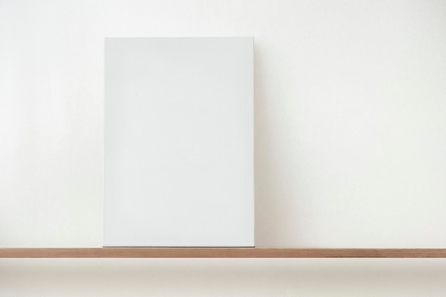 Free Photo blank white canvas on a wooden shelf