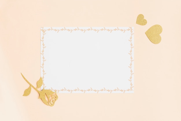 Blank white card with golden heart and rose on colored backdrop