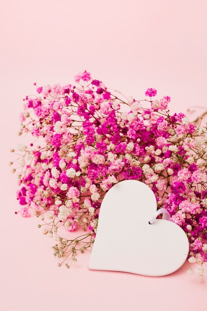 Blank white heart shape with baby's-breath flowers on pink background